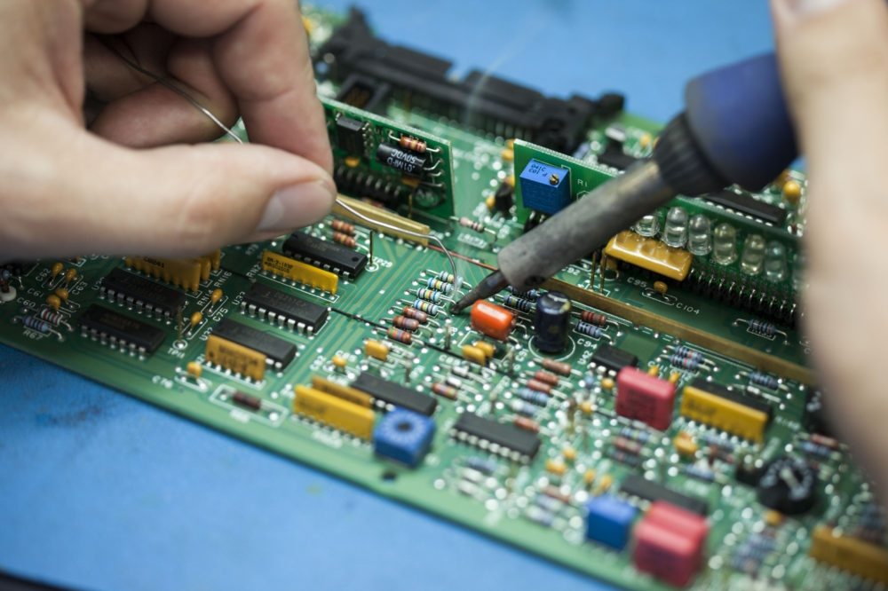 Technician soldering a component onto an industrial drive control board